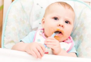 A baby eating with a spoon