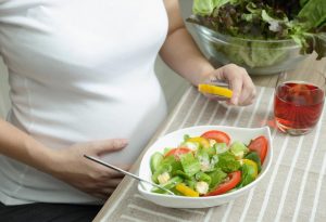 En gravid kvinna som äter en sallad