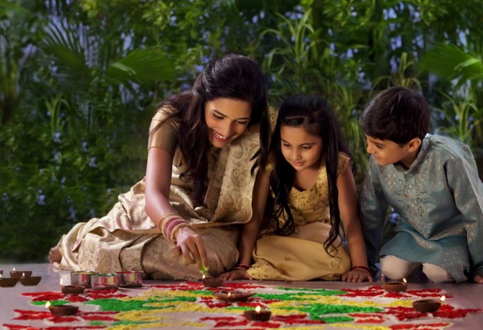 A mother making rangoli with her kids