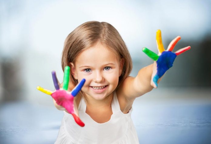 A little girl with paint all over her hands