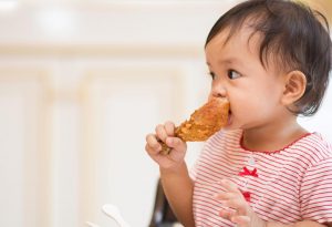 A baby eating chicken