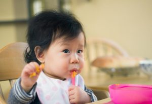 A baby girl eating mashed sweet potatoes