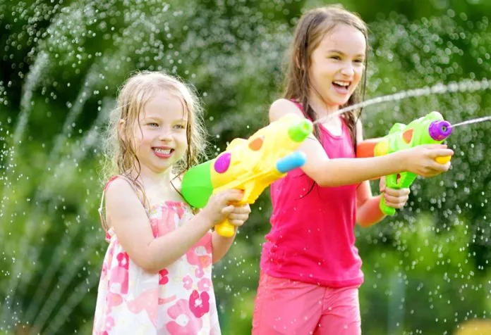 Two little girls playing with water guns