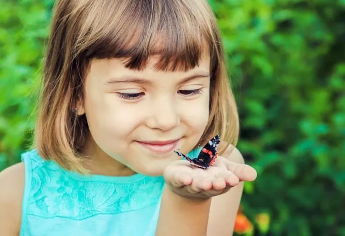 A little girl with a butterfly resting on her palm