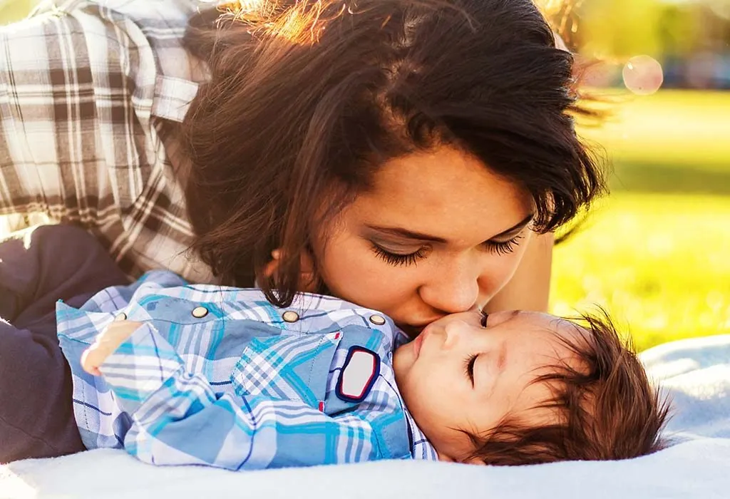 A mother kissing her sleeping baby