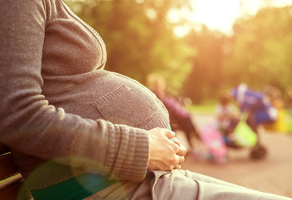 A pregnant woman sitting on a park bench