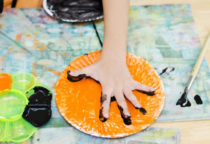 A child painting on a paper plate