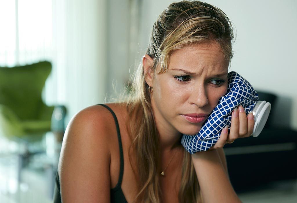 Woman using ice-pack for tooth ache