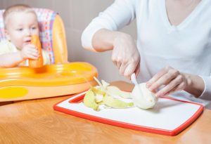 A mother slicing pear for her baby