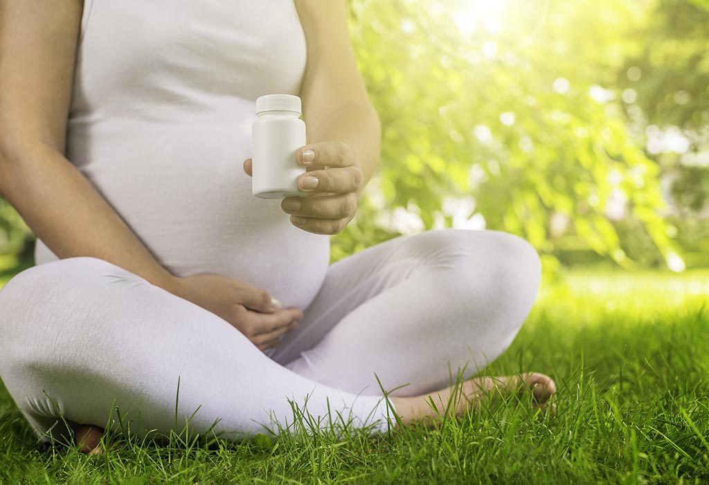 A pregnant woman holding vitamin capsules in her hand