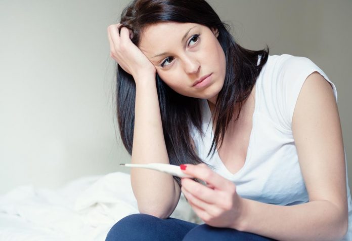 A disheartened woman with a pregnancy test stick