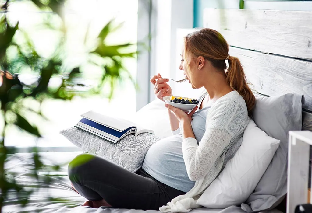 A pregnant woman eating her meal. A pregnant woman eating her meal.