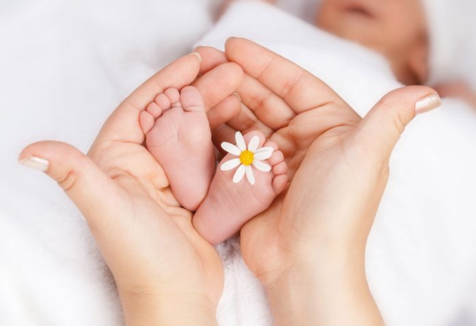 A mother holding her baby's feet with a flower on it