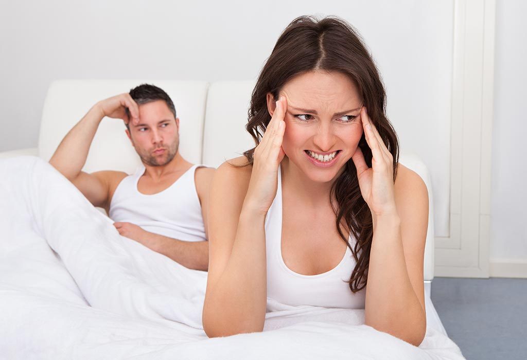 An upset woman sitting in bed with her husband.