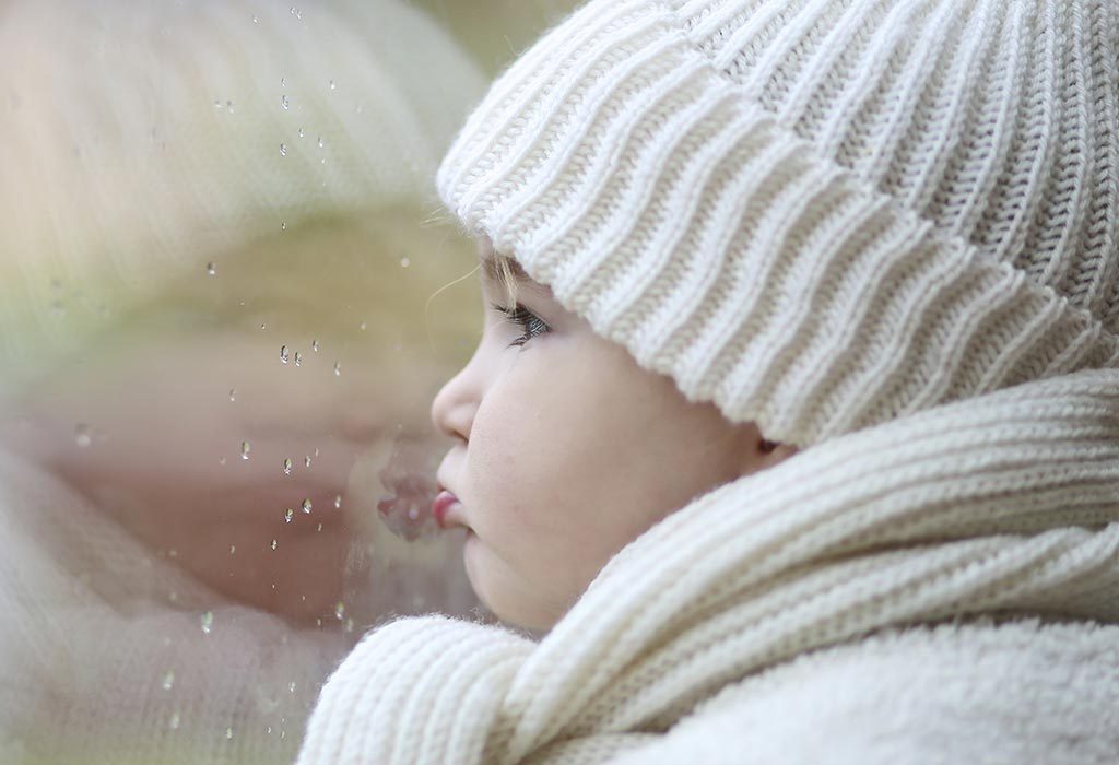 A baby staring at the rain through the window