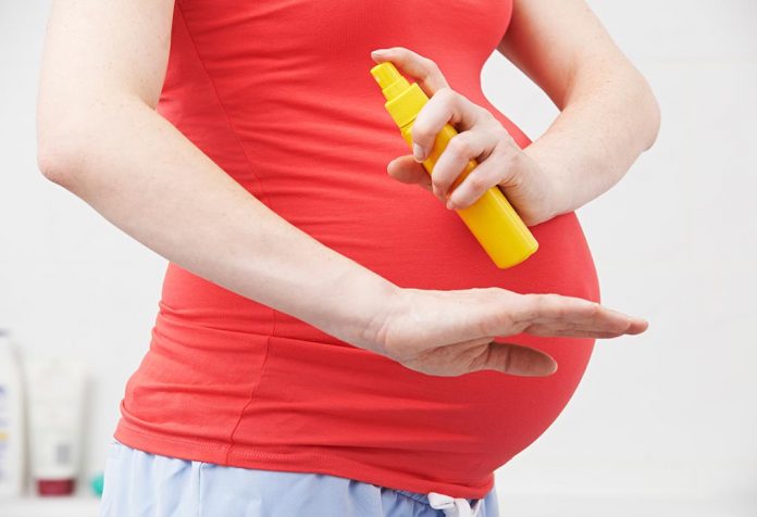 A pregnant woman using a mosquito repellent