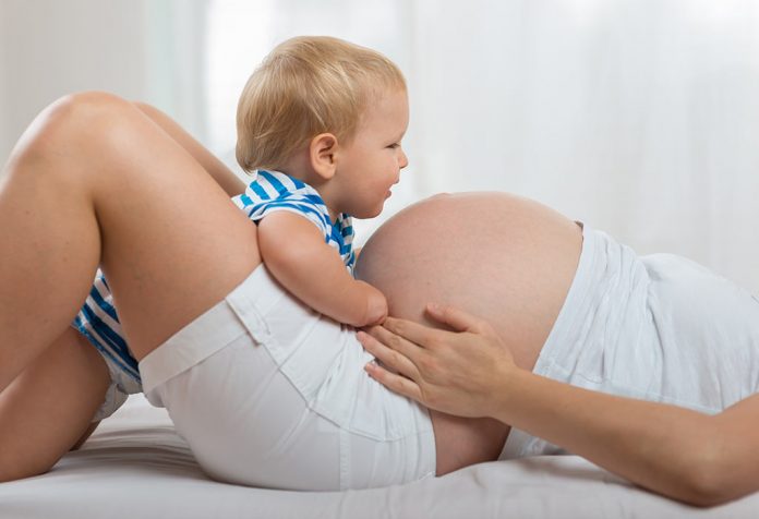 A pregnant mother playing with her infant