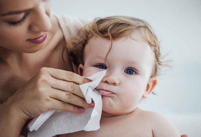 A mother cleaning her baby with baby wipes.