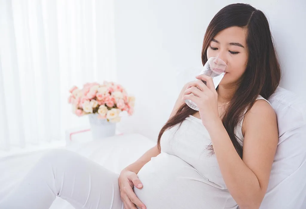 A pregnant woman drinks water A pregnant woman drinks water