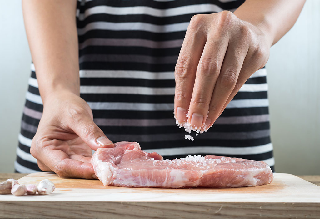 Vrouw doet zout op biefstuk