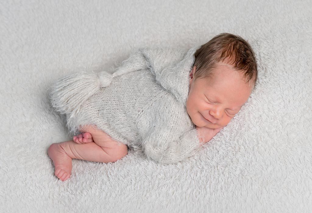  A baby boy smiling while asleep.