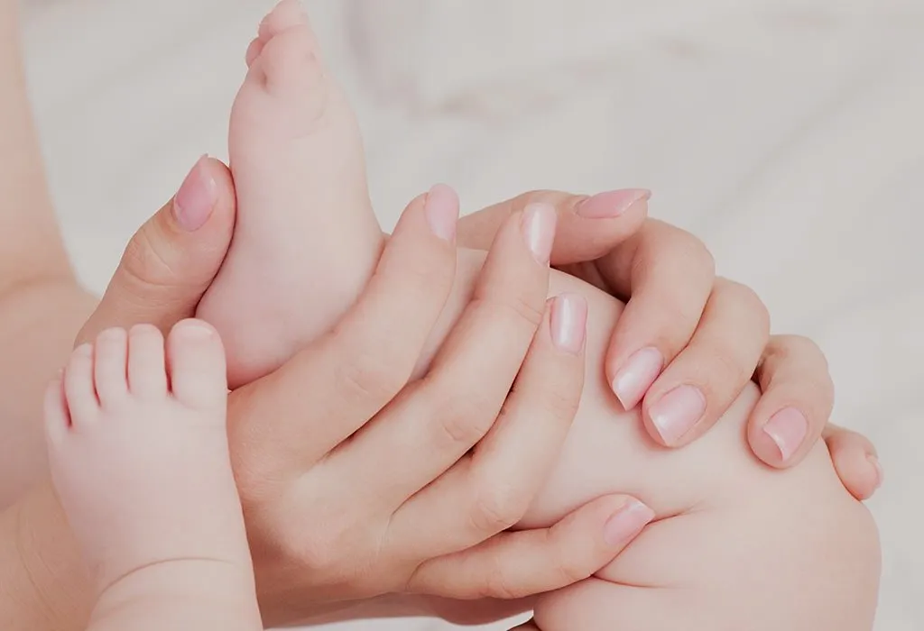 Closeup of mother hands holding cute tiny baby feet, showing baby foot.  Pink Background. Horizontal. Stock Photo