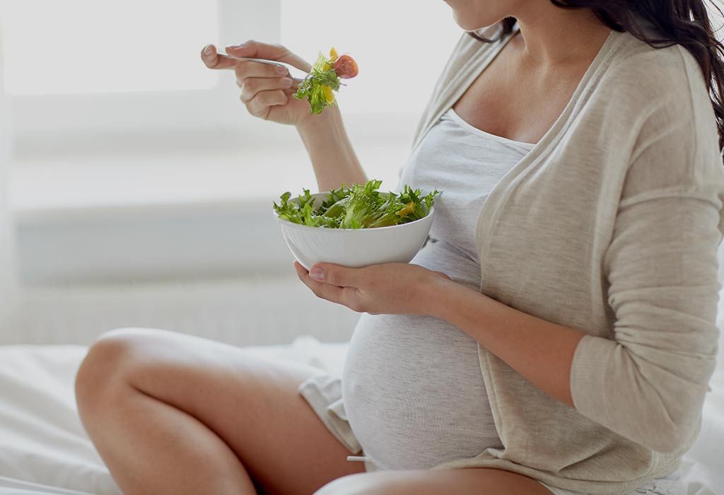 A pregnant woman eats salad