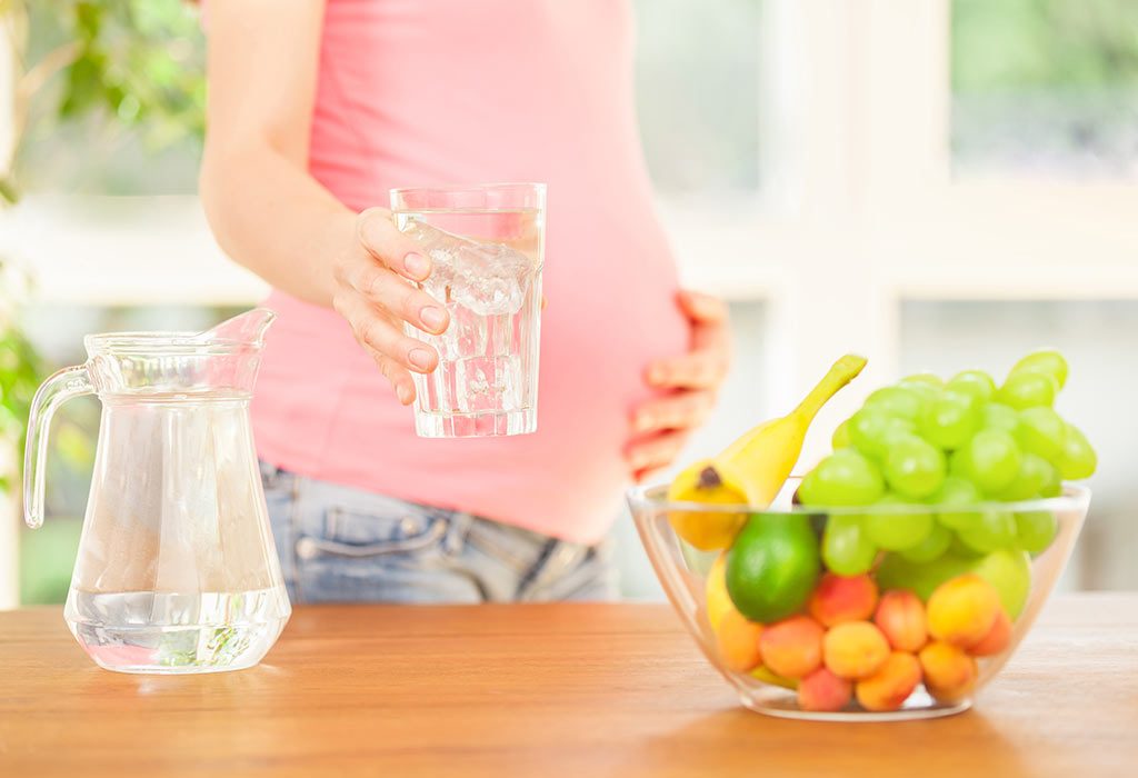 A pregnant woman with a glass of water in her hand