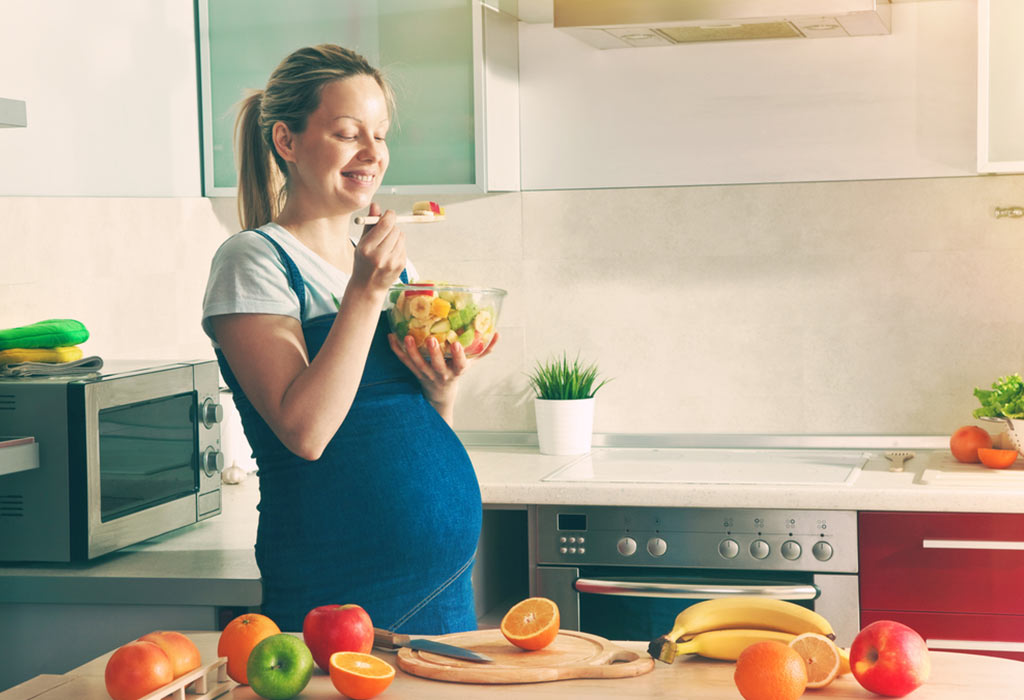 raskaana oleva nainen syö hedelmiä