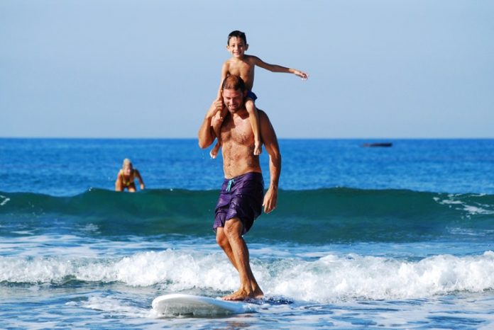 Father lifting Son while riding Surfboard