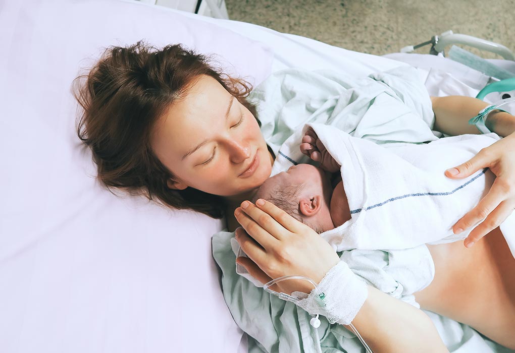 A mother holding her newborn close in the hospital