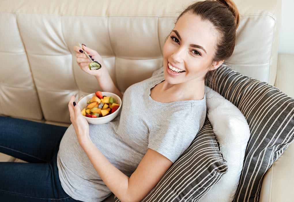 A pregnant woman eating fruit salad