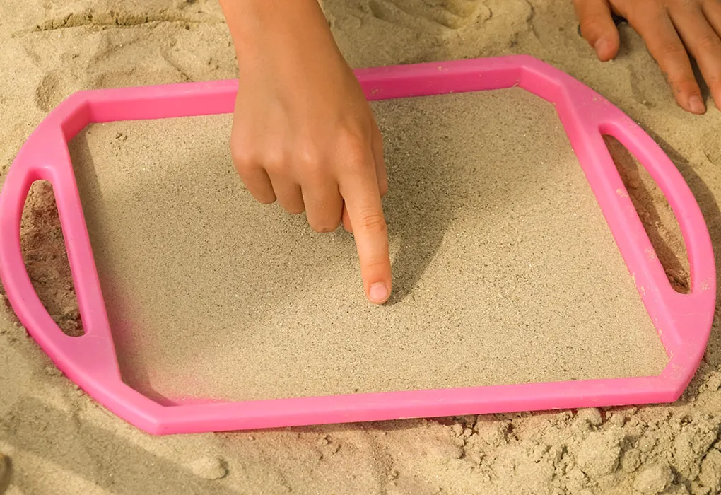 Child writing in sand