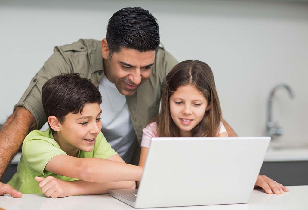 A boy showing his father something on a laptop