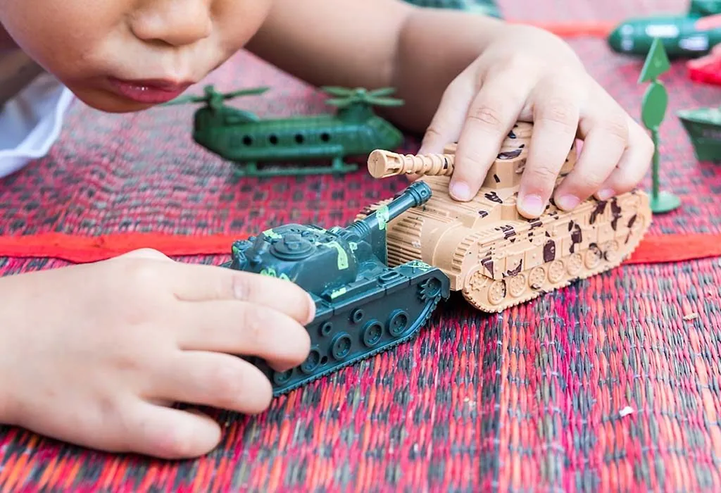 A boy playing with tank toys