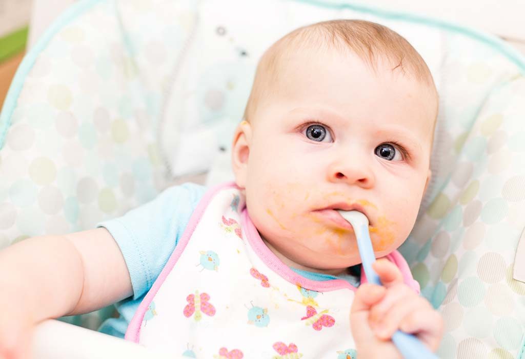 give your baby the spoon to hold so he can practice taking food by himself