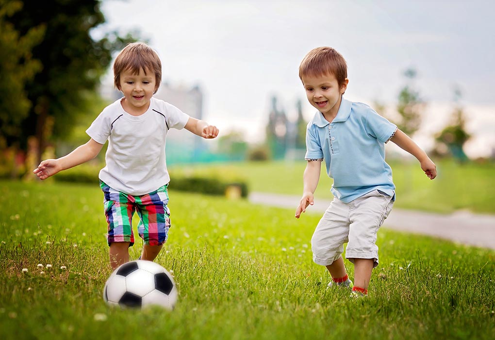 Two boys playing soccer in a park