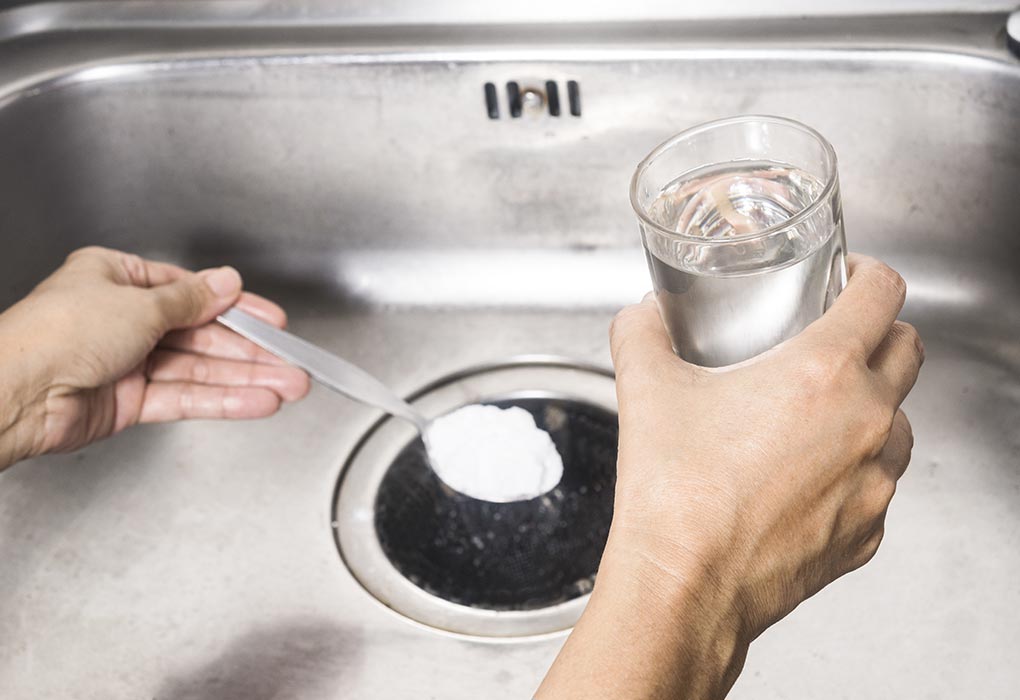 A woman pours baking soda in the sink