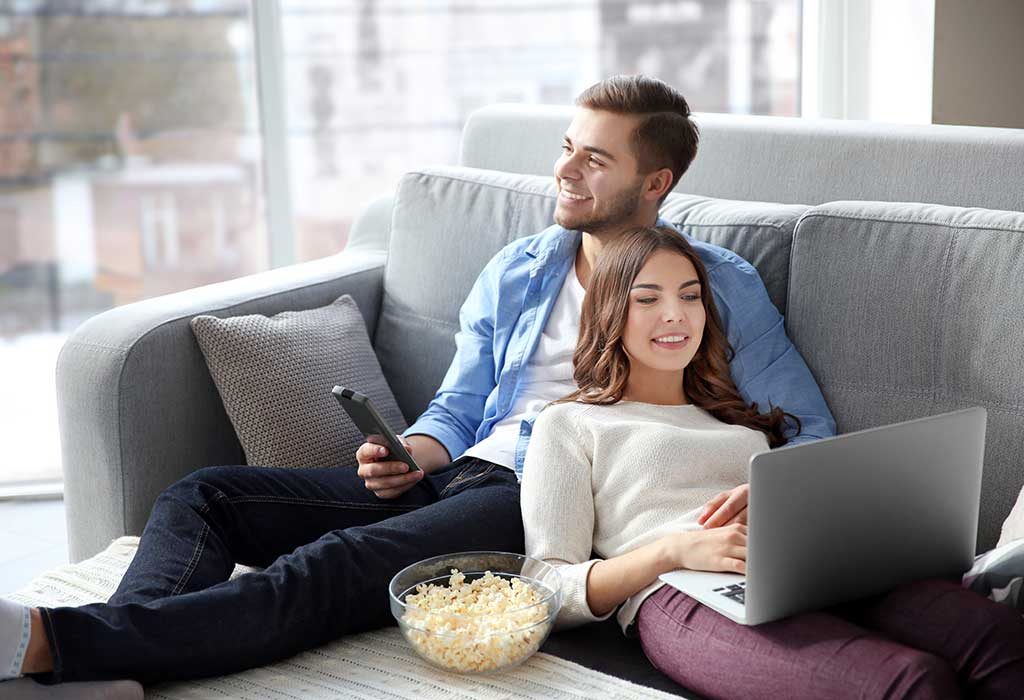 A man watching TV and woman using a laptop