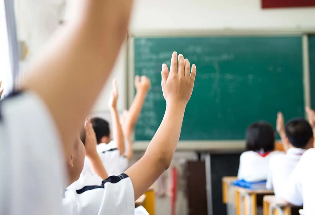 Children raising hand to answer in class