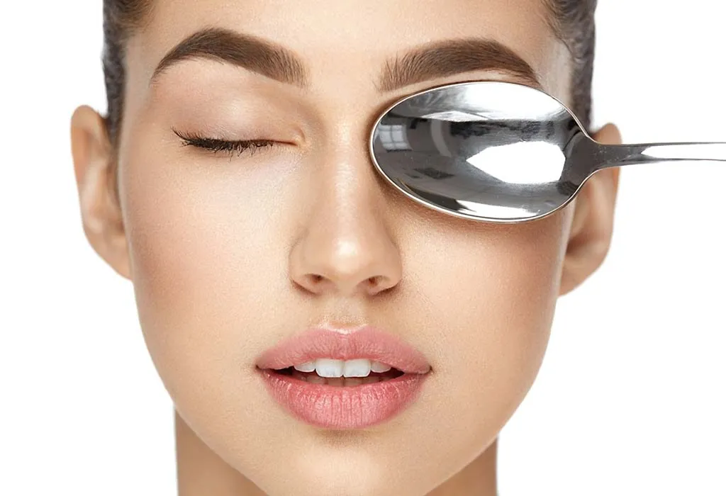 A woman placing a chilled spoon on her eyes