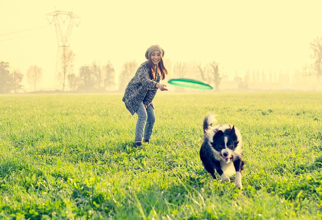 A woman playing go fetch with her dog