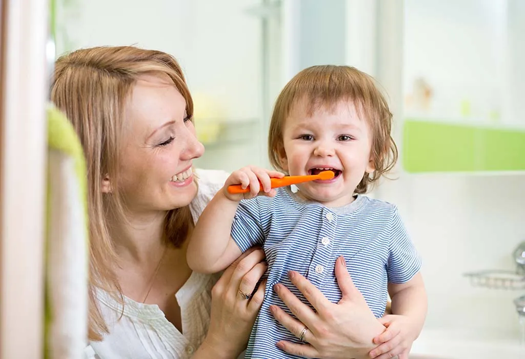 A mother helping a child brush his teeth