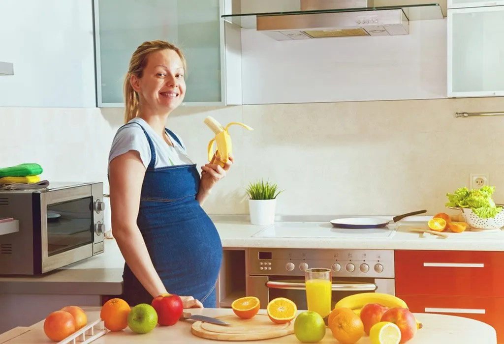 A pregnant woman eating banana