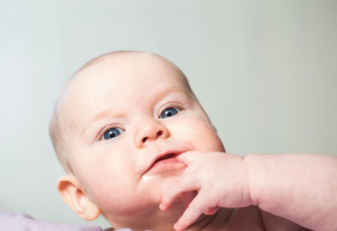 baby putting hands in mouth and vomiting