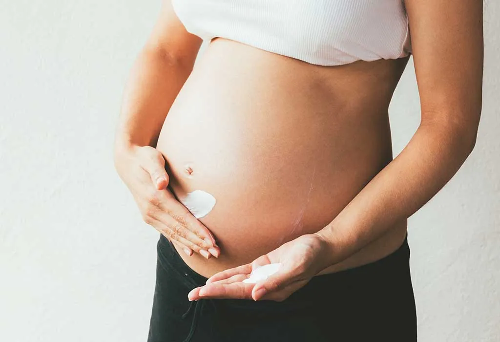 pregnant woman applying moisturiser
