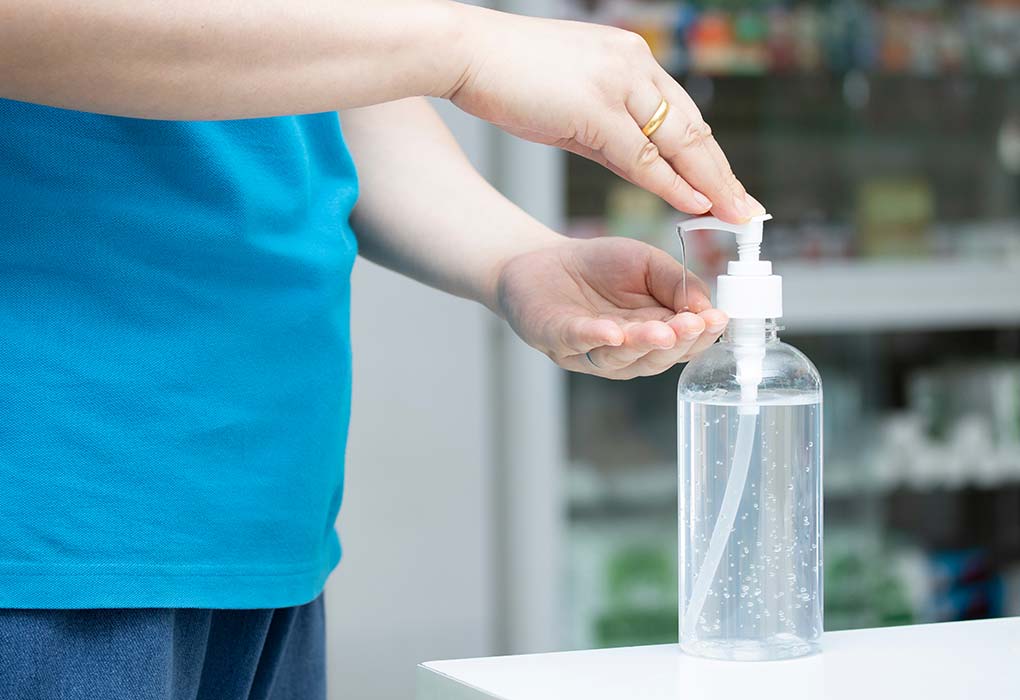 A pregnant woman using sanitiser