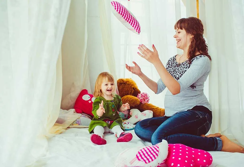 Mom n toddler playing pass with a pillow