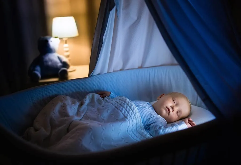 A baby sleeping in a bassinet at night