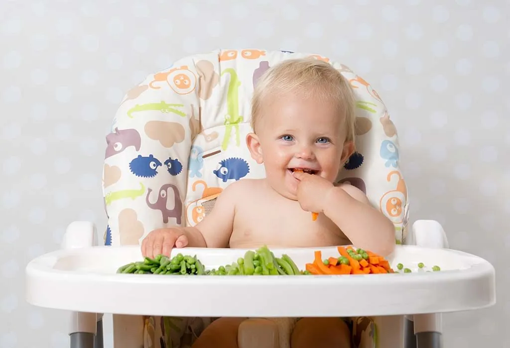 A baby eating sitting on a high chair